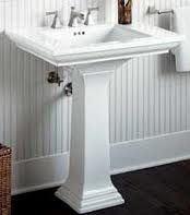 A white pedestal sink in a bathroom next to a toilet.