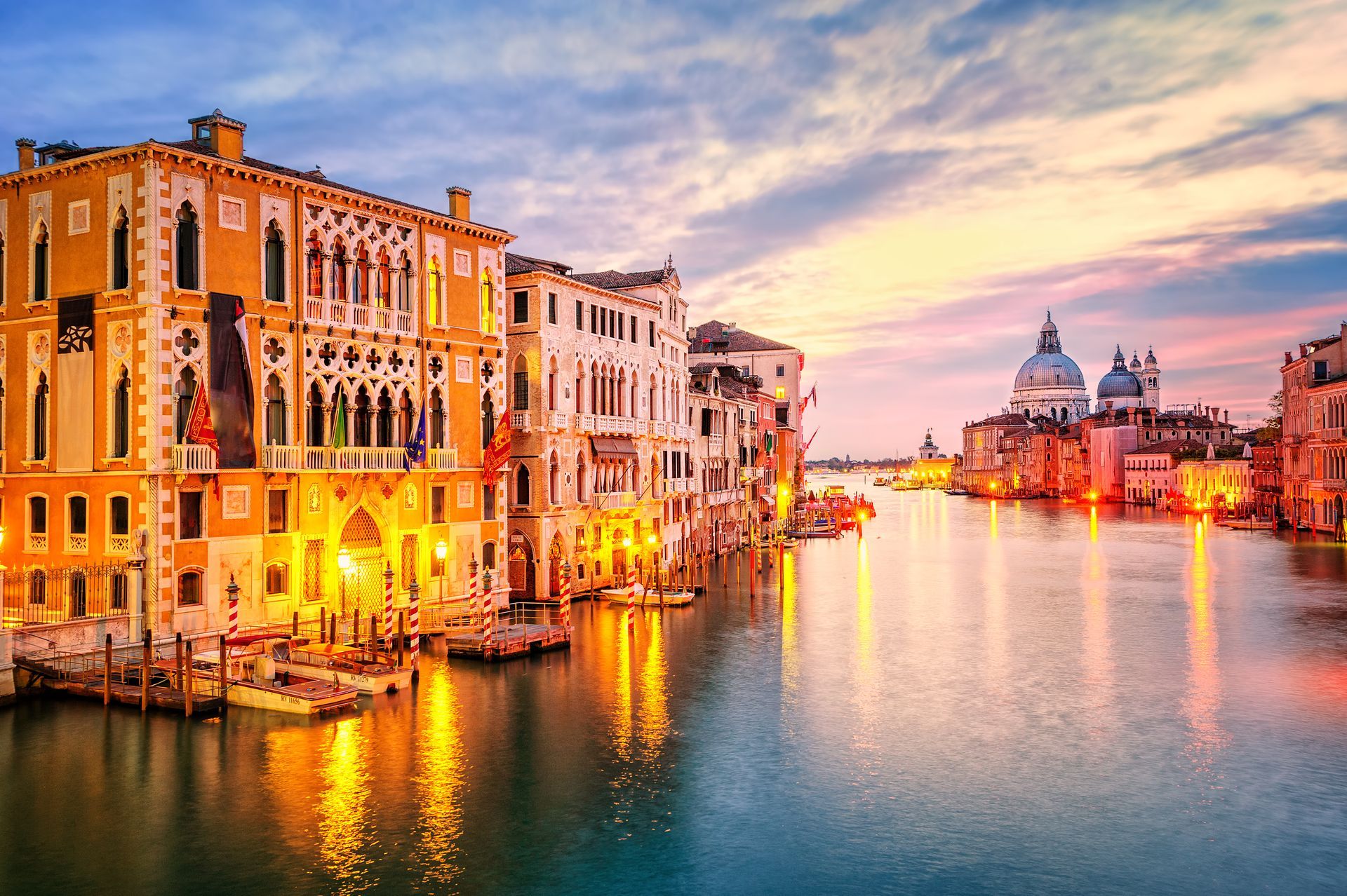 A large body of water surrounded by buildings in venice at sunset.