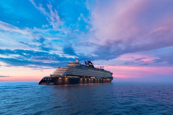 A cruise ship is floating on top of a large body of water at sunset.