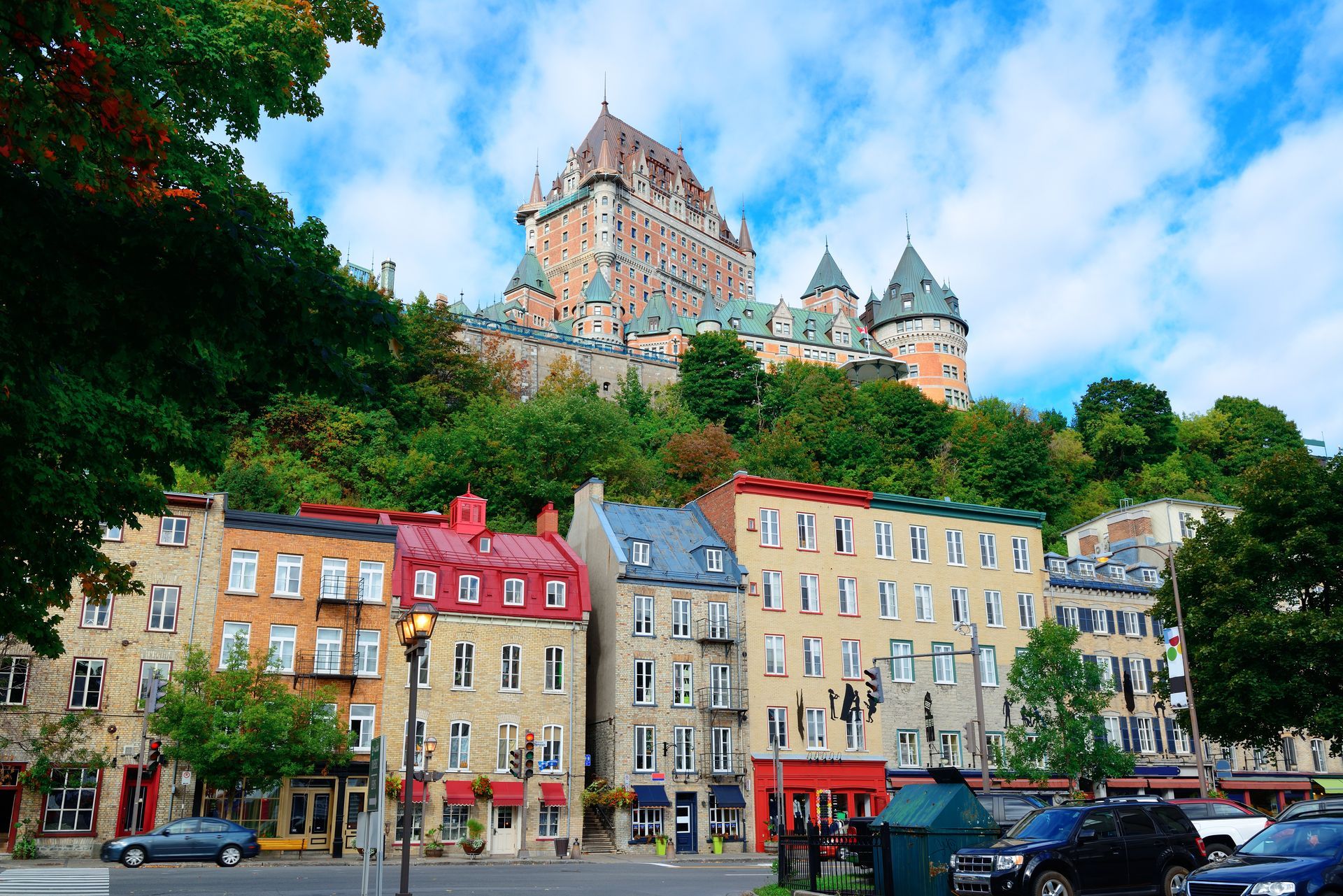A large castle sits on top of a hill behind a row of buildings