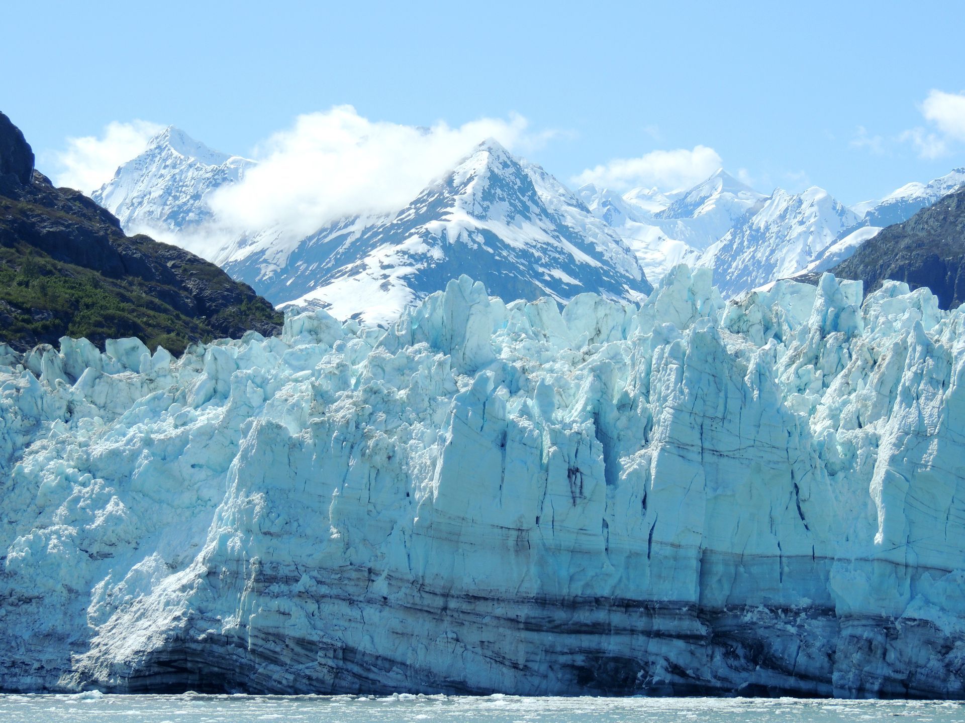A large glacier is surrounded by snow covered mountains