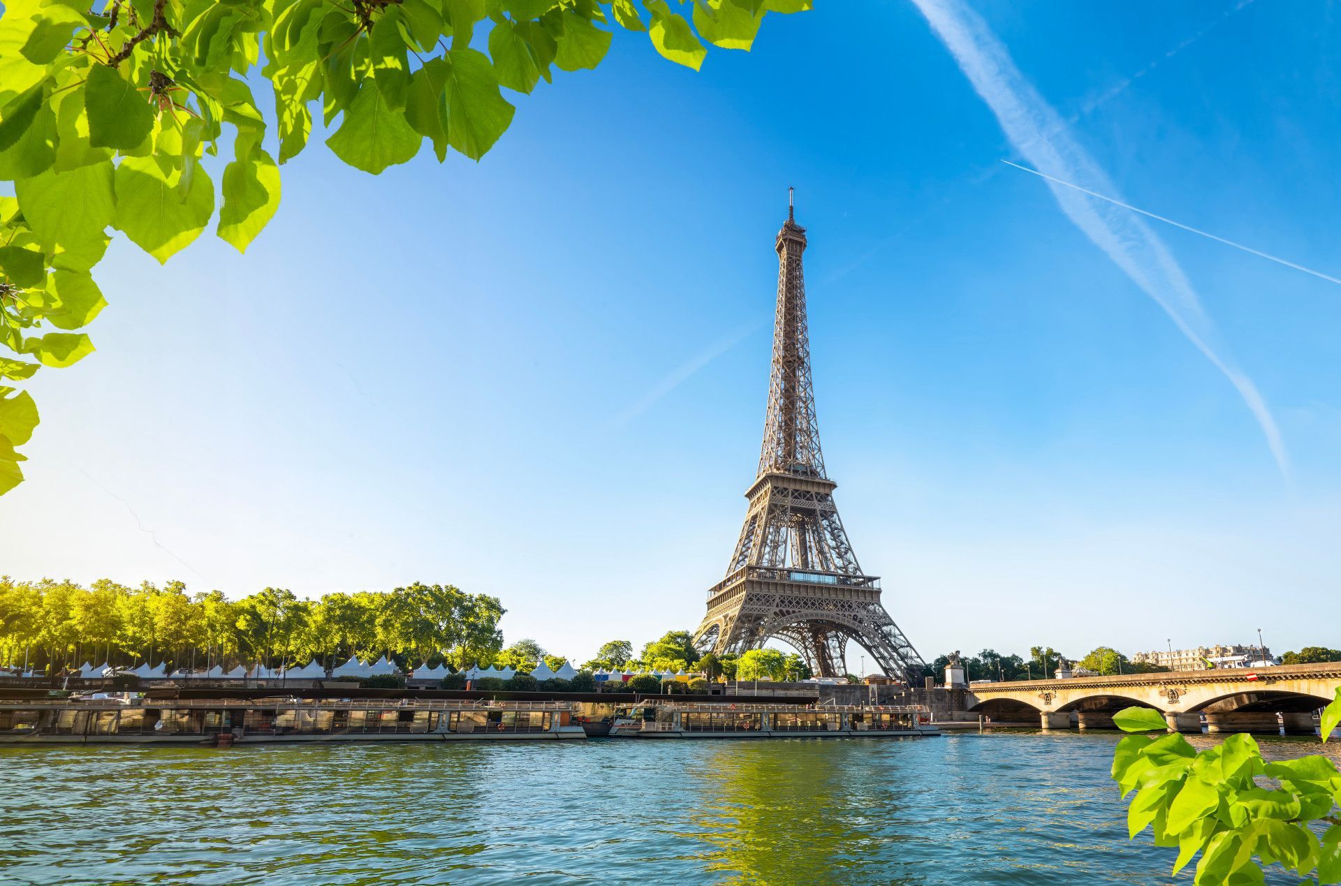The eiffel tower is surrounded by trees and water in paris.