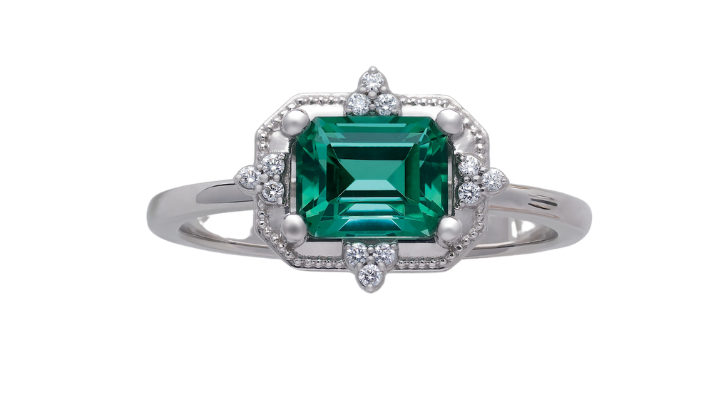 a ring with an emerald and diamonds on a white background 