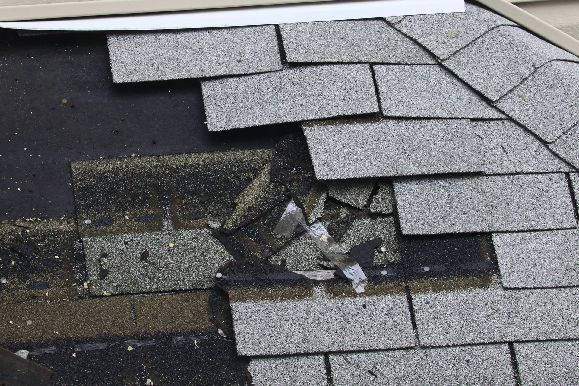 Damaged roof shingles showing cracks and missing pieces near the edge.
