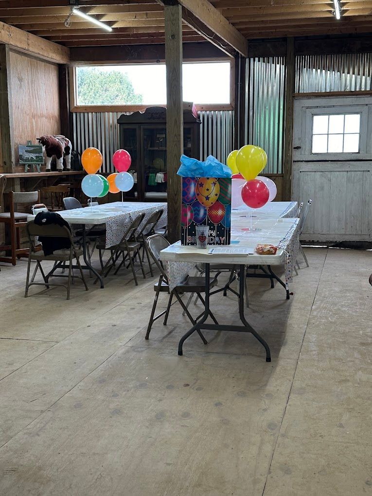 A room with tables and chairs decorated with balloons for a birthday party.