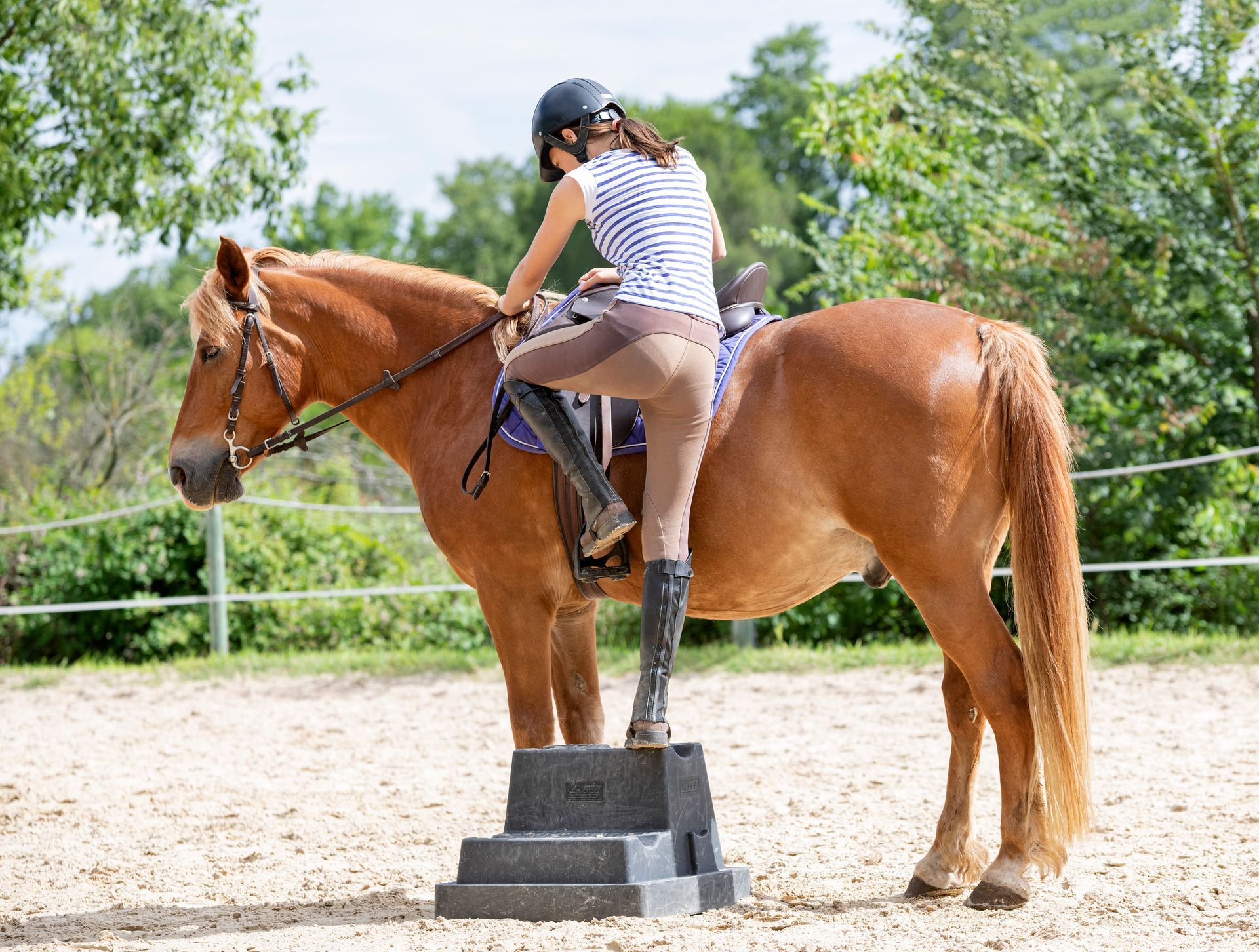 A woman is riding on the back of a brown horse.