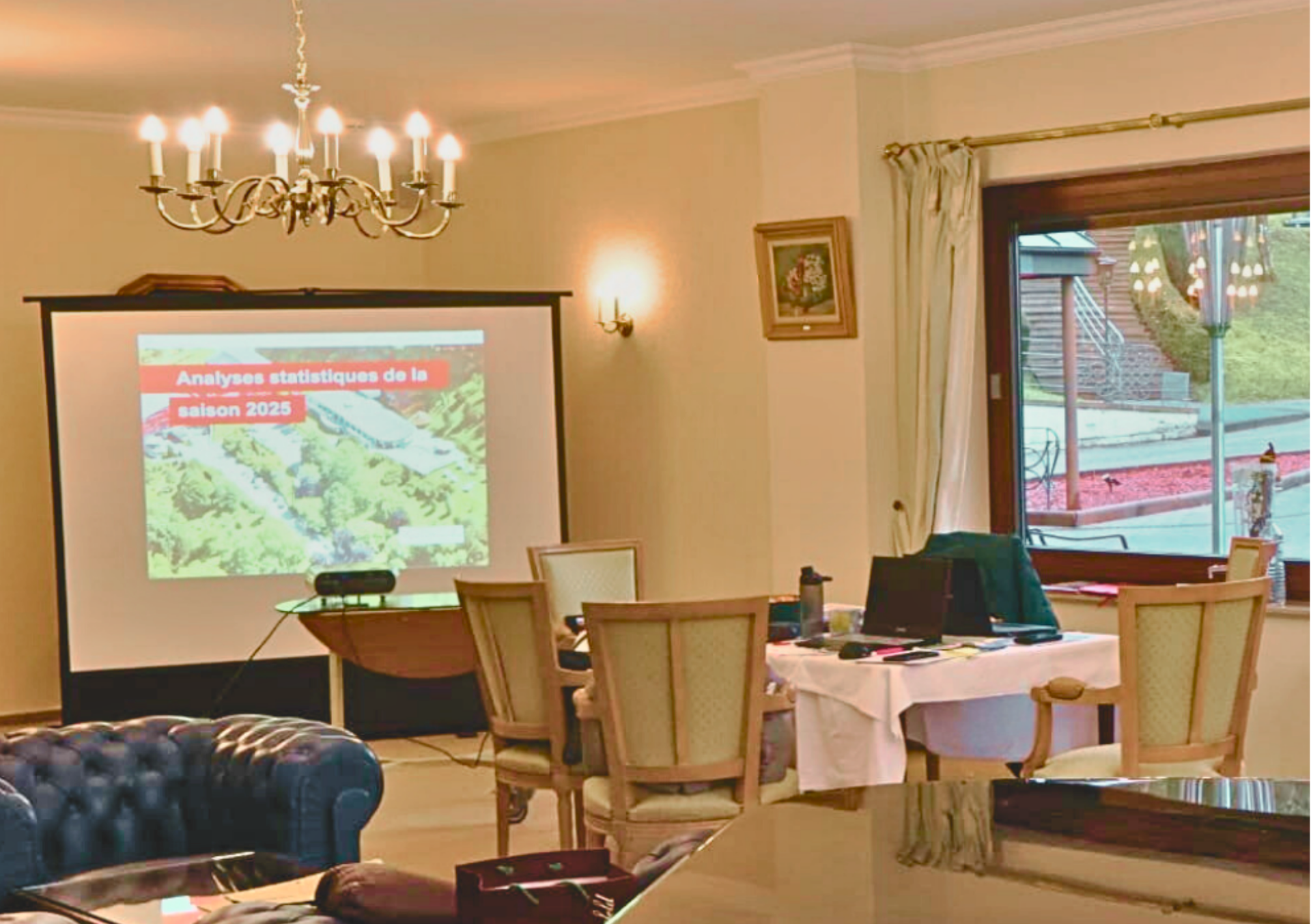 Une longue table de réunion rectangulaire dressée pour un rassemblement, entourée de chaises dans une pièce formelle.