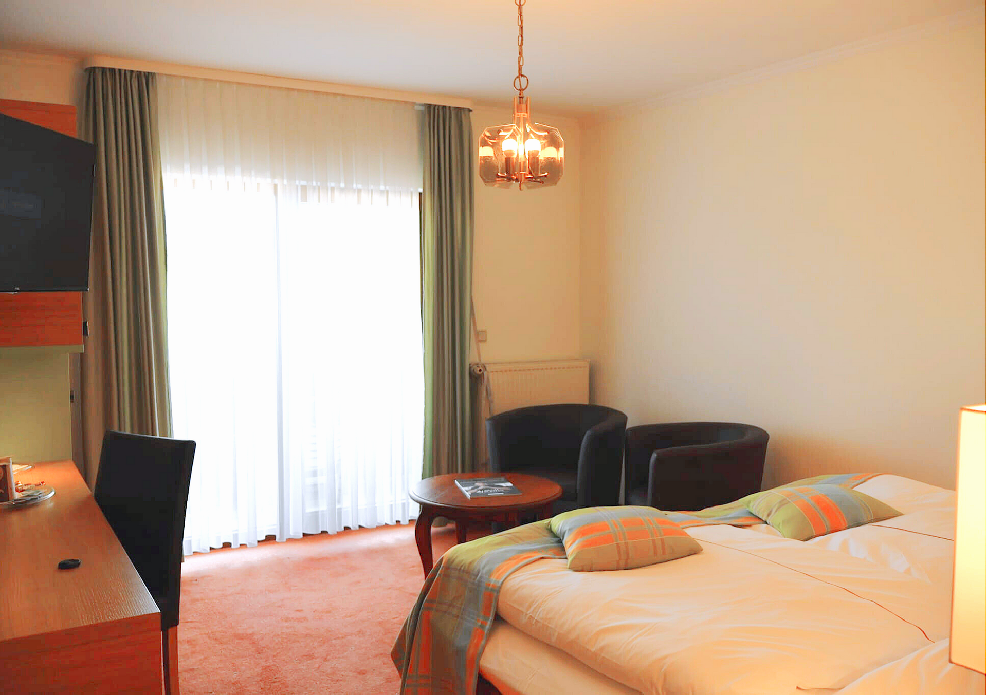 Chambre d'hôtel avec un lit, des chaises, une table et une fenêtre avec des rideaux.