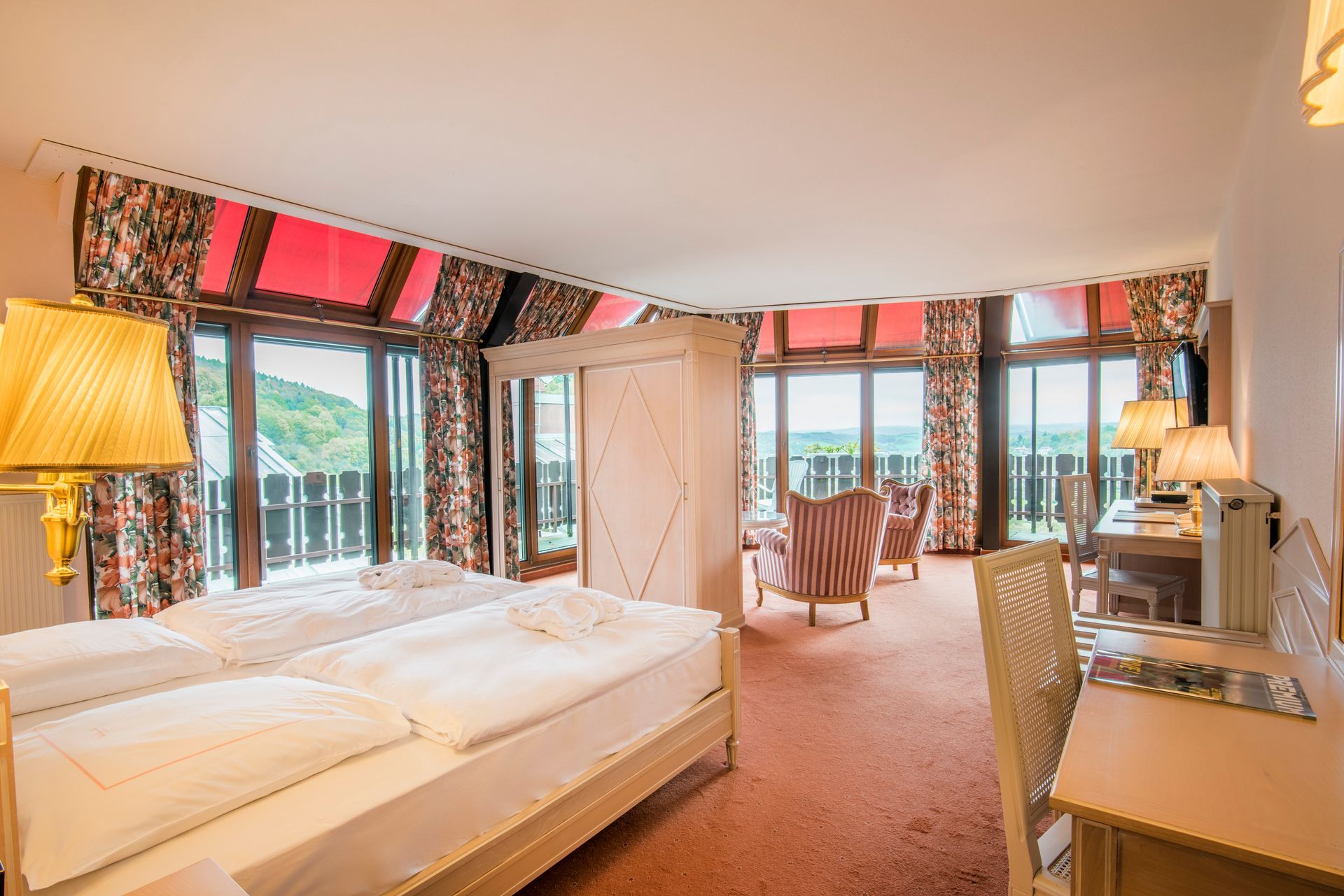 Chambre d'hôtel avec deux lits, bureau, chaises et balcon avec vue panoramique.