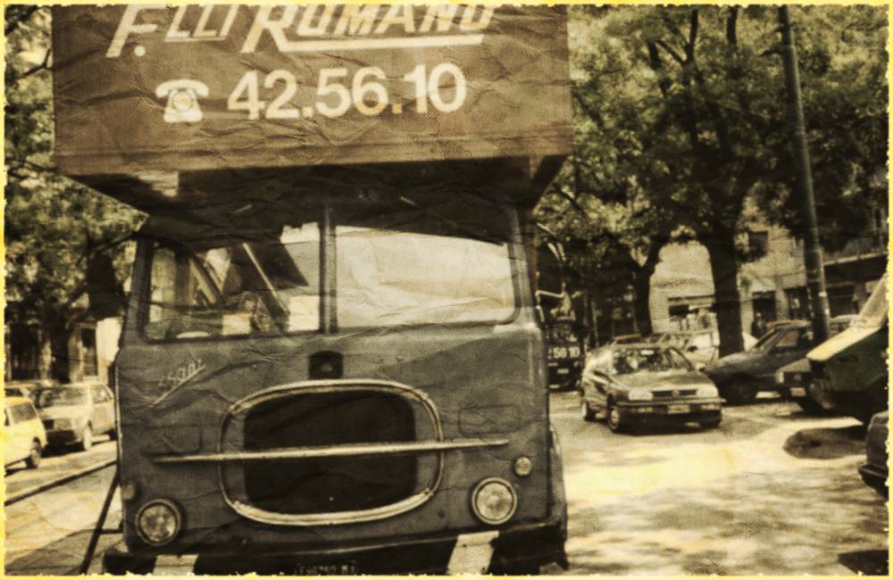 Un camion betoniera sta percorrendo una strada sterrata davanti a un edificio.