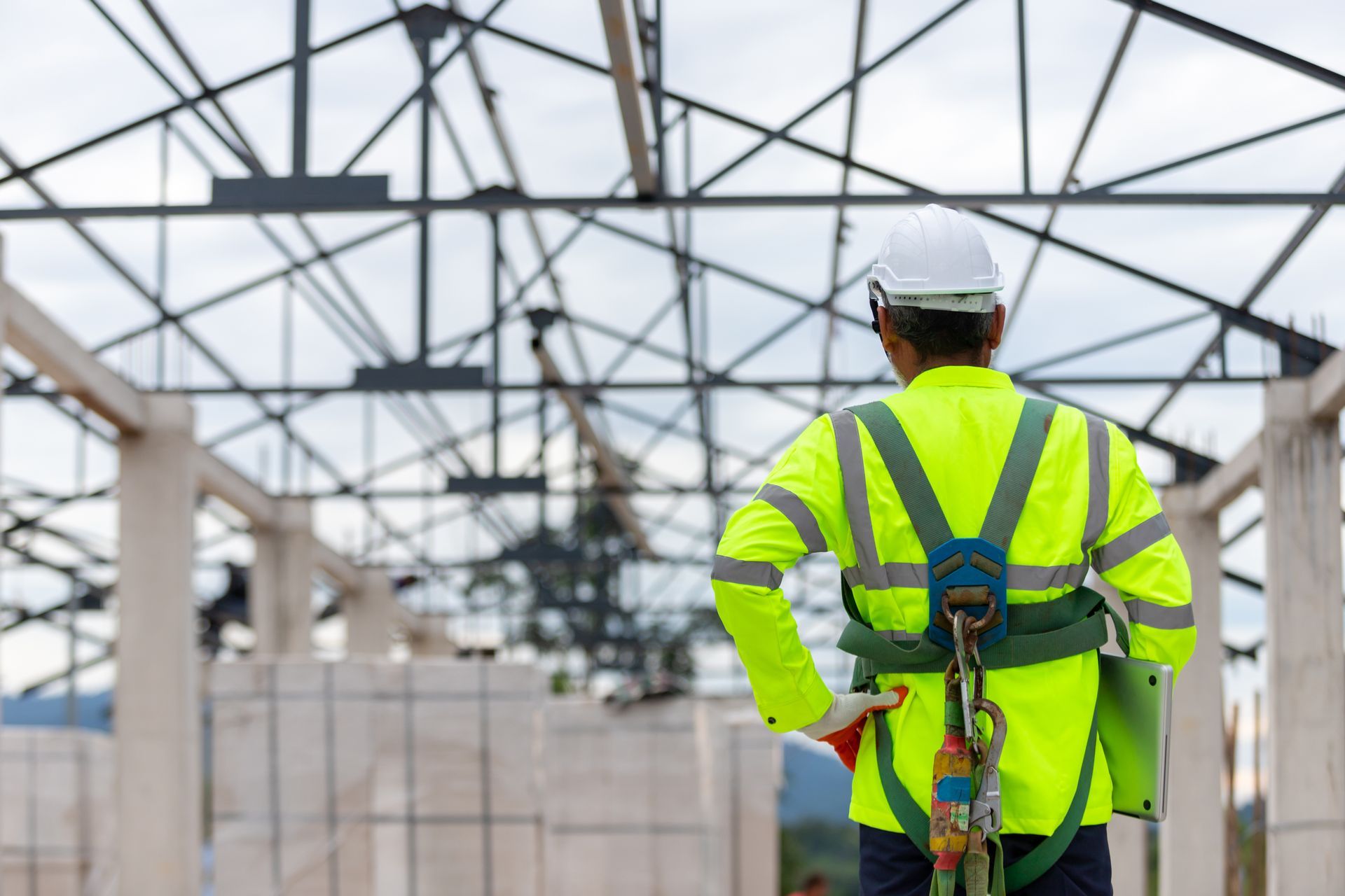 Construction worker in safety gear observing a building frame from inside the structure.