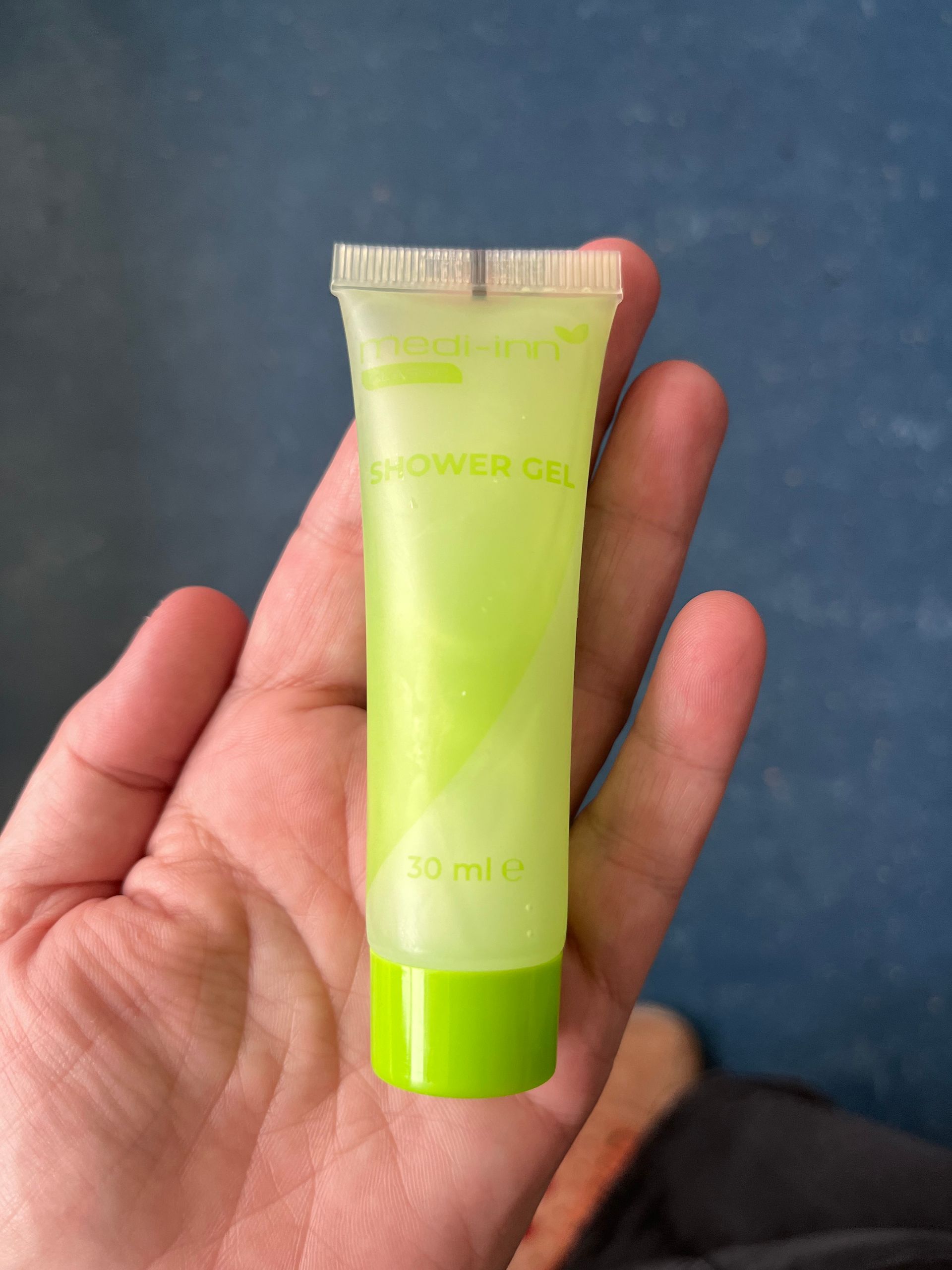 hand holding a light green tube of shampoo