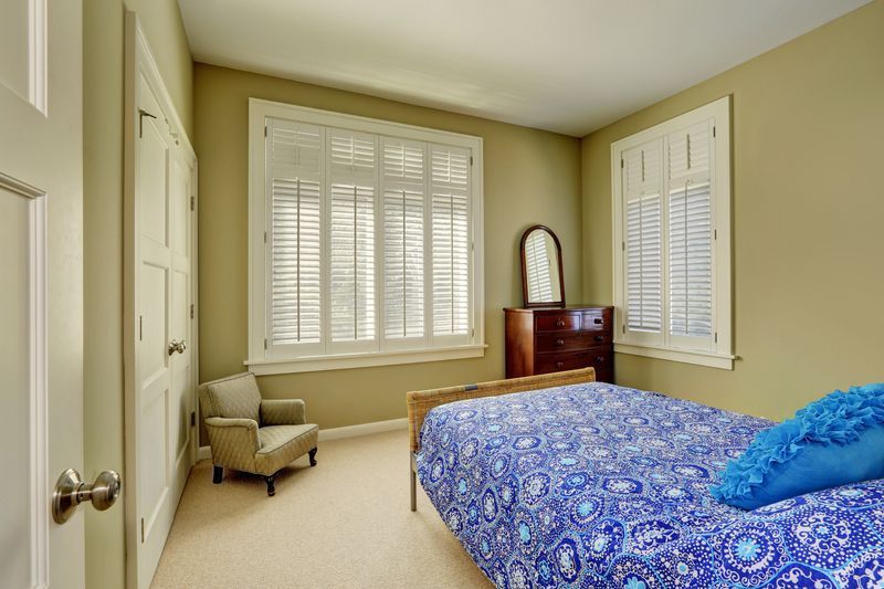 A bedroom with a bed , chair , dresser and mirror