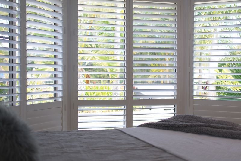 A bedroom with a bed and shutters on the windows.