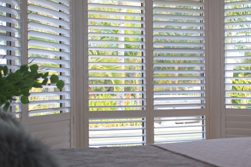 A bedroom with white shutters on the windows