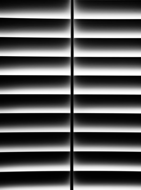 A black and white photo of a window with blinds.