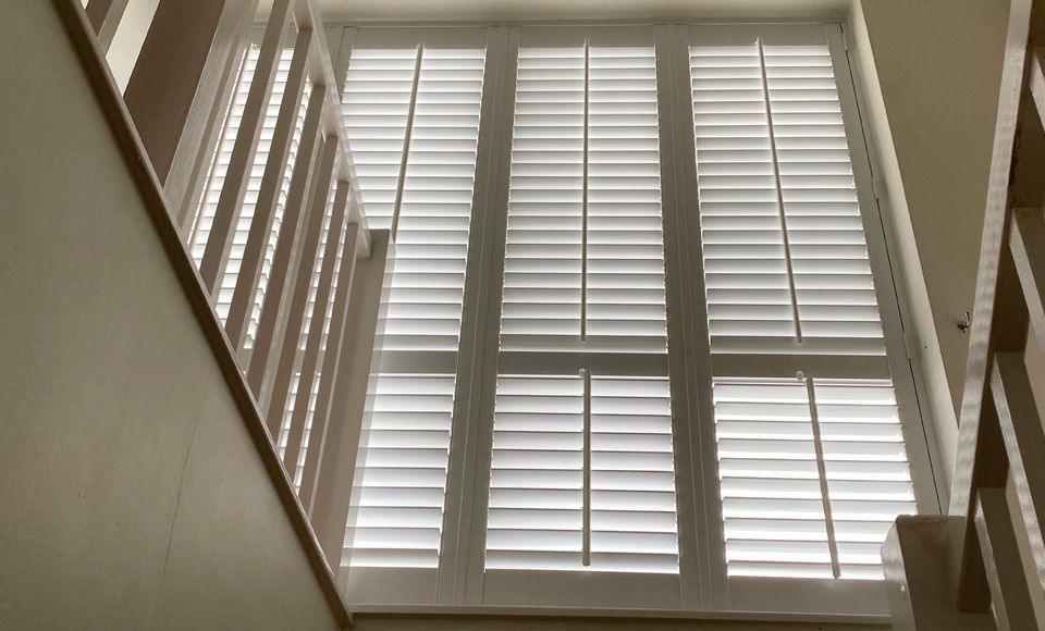 Looking up at a window with white shutters on it