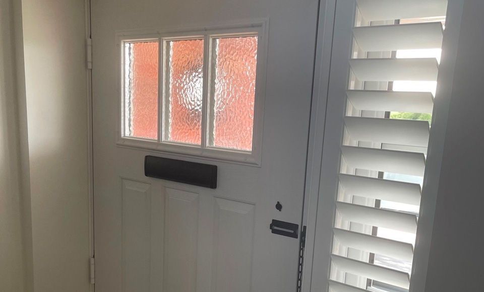 A white door with shutters on it and a window.