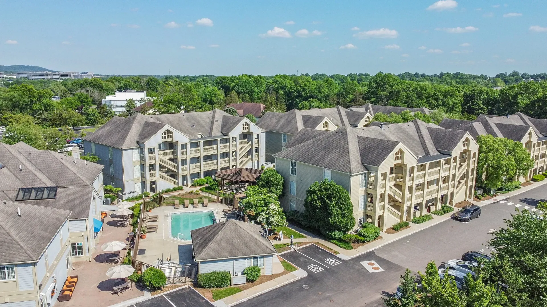 An aerial view of a residential area with a swimming pool surrounded by trees.