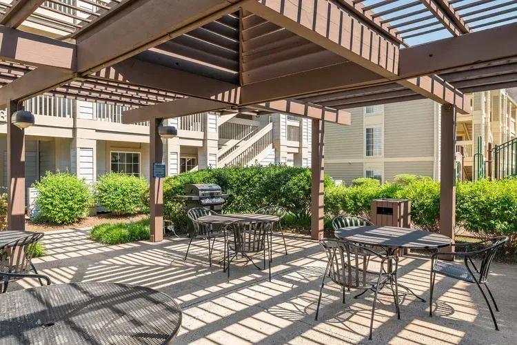 A patio area with tables and chairs under a pergola.
