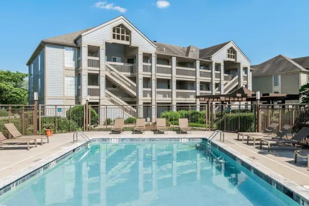 A large swimming pool is in front of a large apartment building.