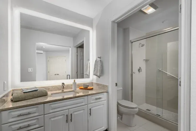 A bathroom with a toilet , sink , mirror and shower.