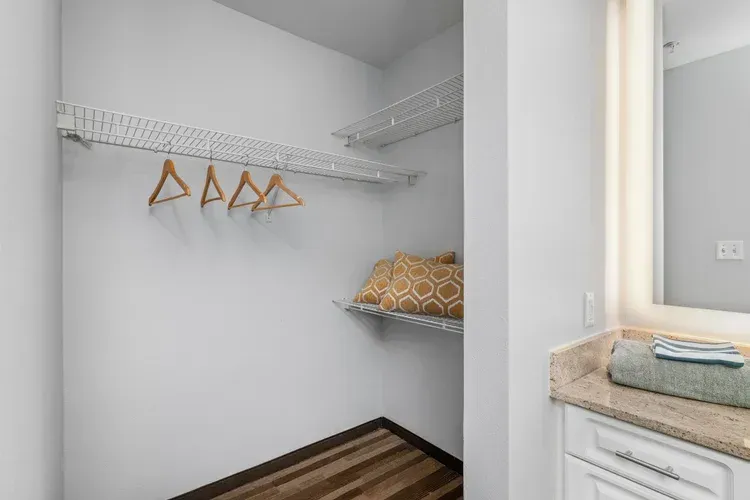 A walk in closet with a vanity and a mirror.