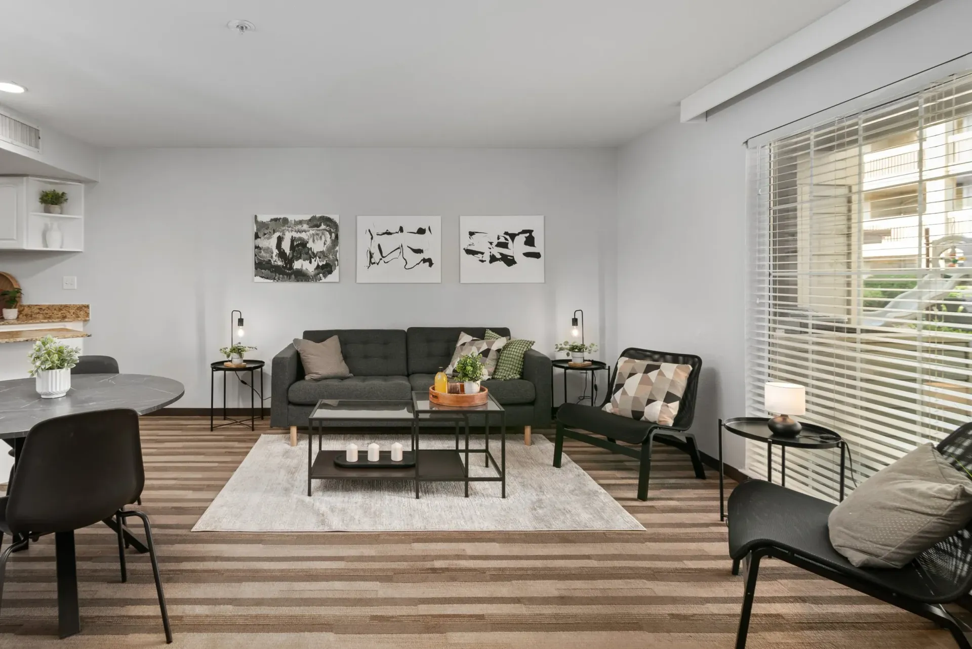 A living room with a couch , chairs , a table and a window.
