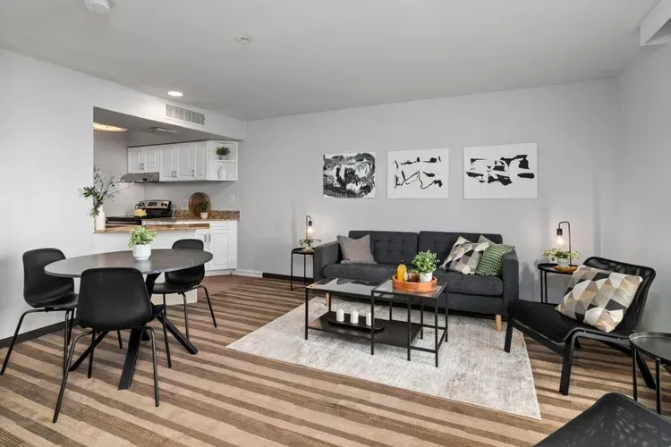 A living room with a couch , chairs , a table and a coffee table.