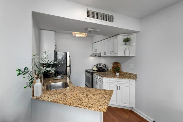 A kitchen with white cabinets , granite counter tops , a refrigerator , stove and sink.