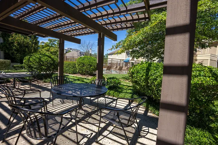 A patio with a table and chairs under a pergola.