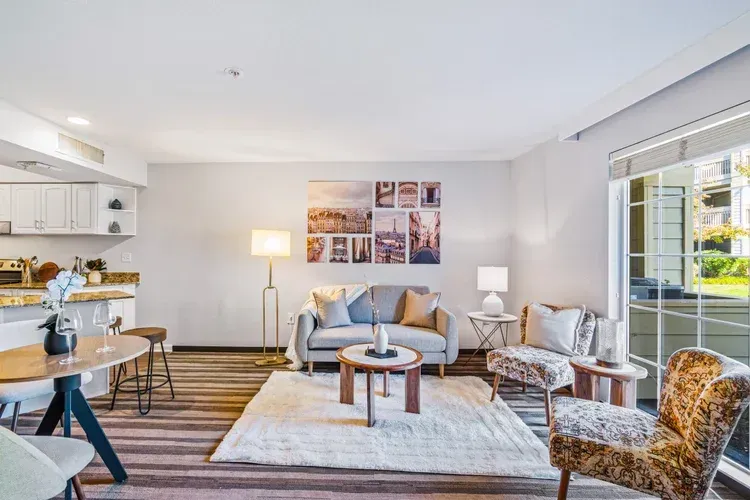A living room with a couch , chairs , a table and a rug.