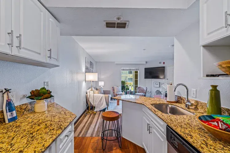 A kitchen with a sink , dishwasher , cabinets and granite counter tops.