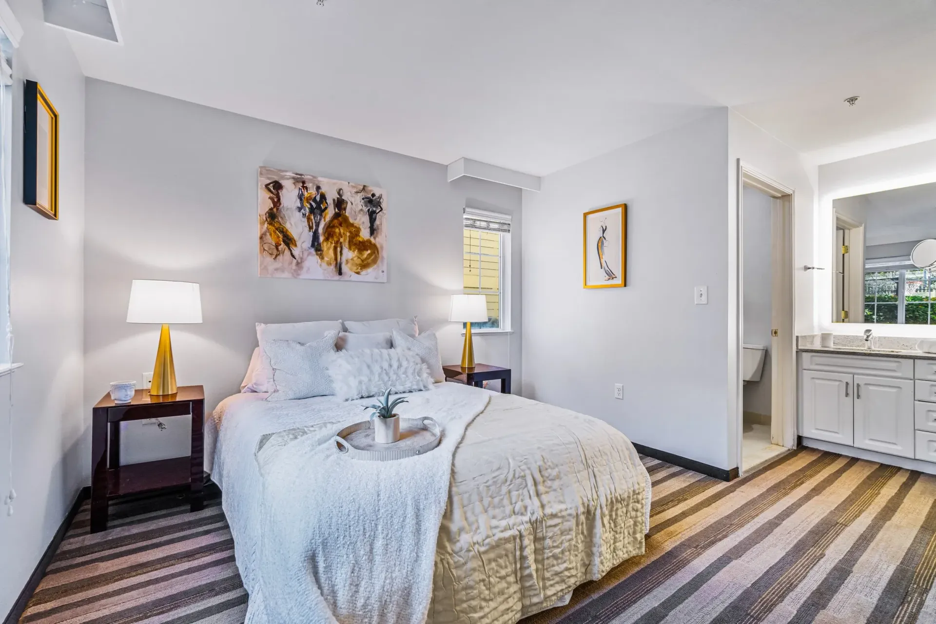 A bedroom with a bed , nightstands , lamps and a bathroom.