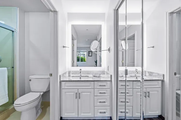 A bathroom with a toilet , sink , mirror and shower.