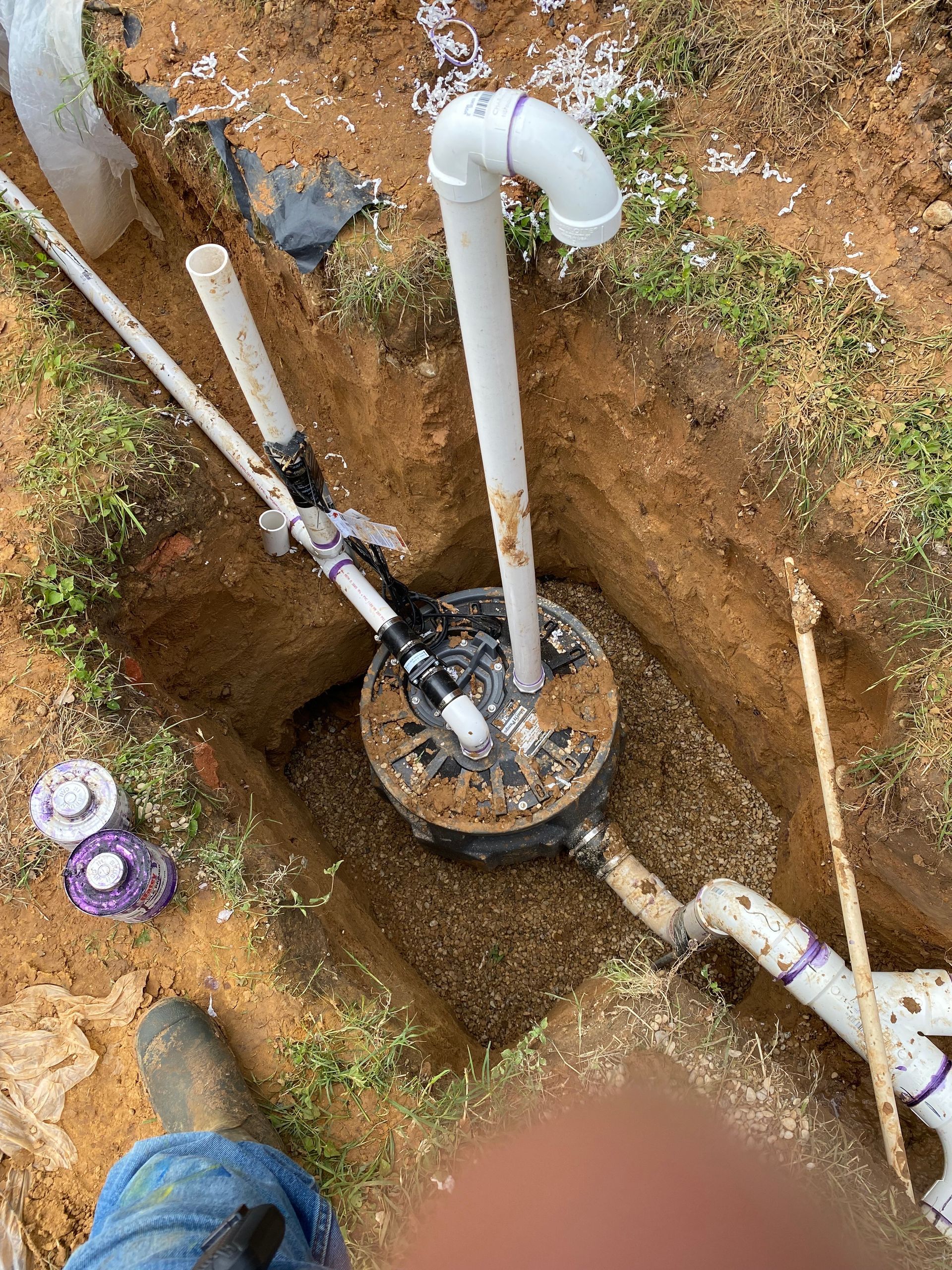 A man is digging a hole in the ground to install a water pump.