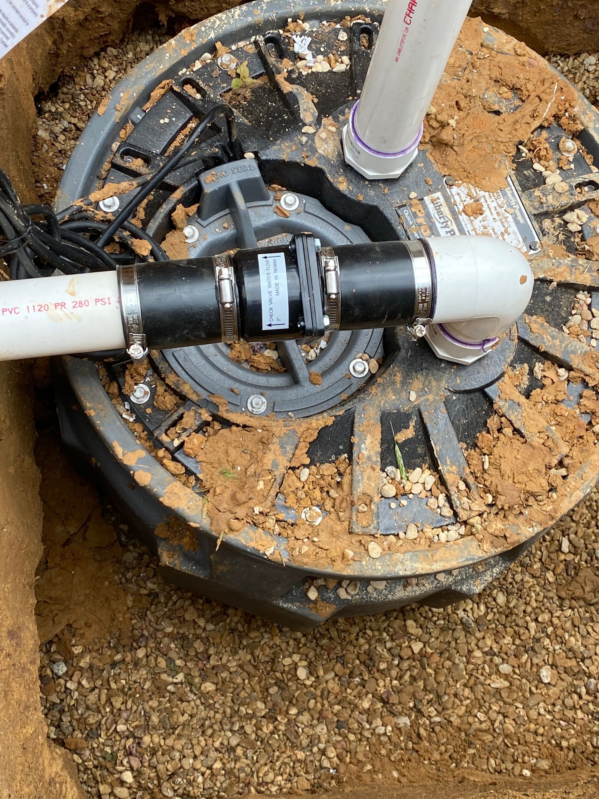 A close up of a sump pump with pipes attached to it.