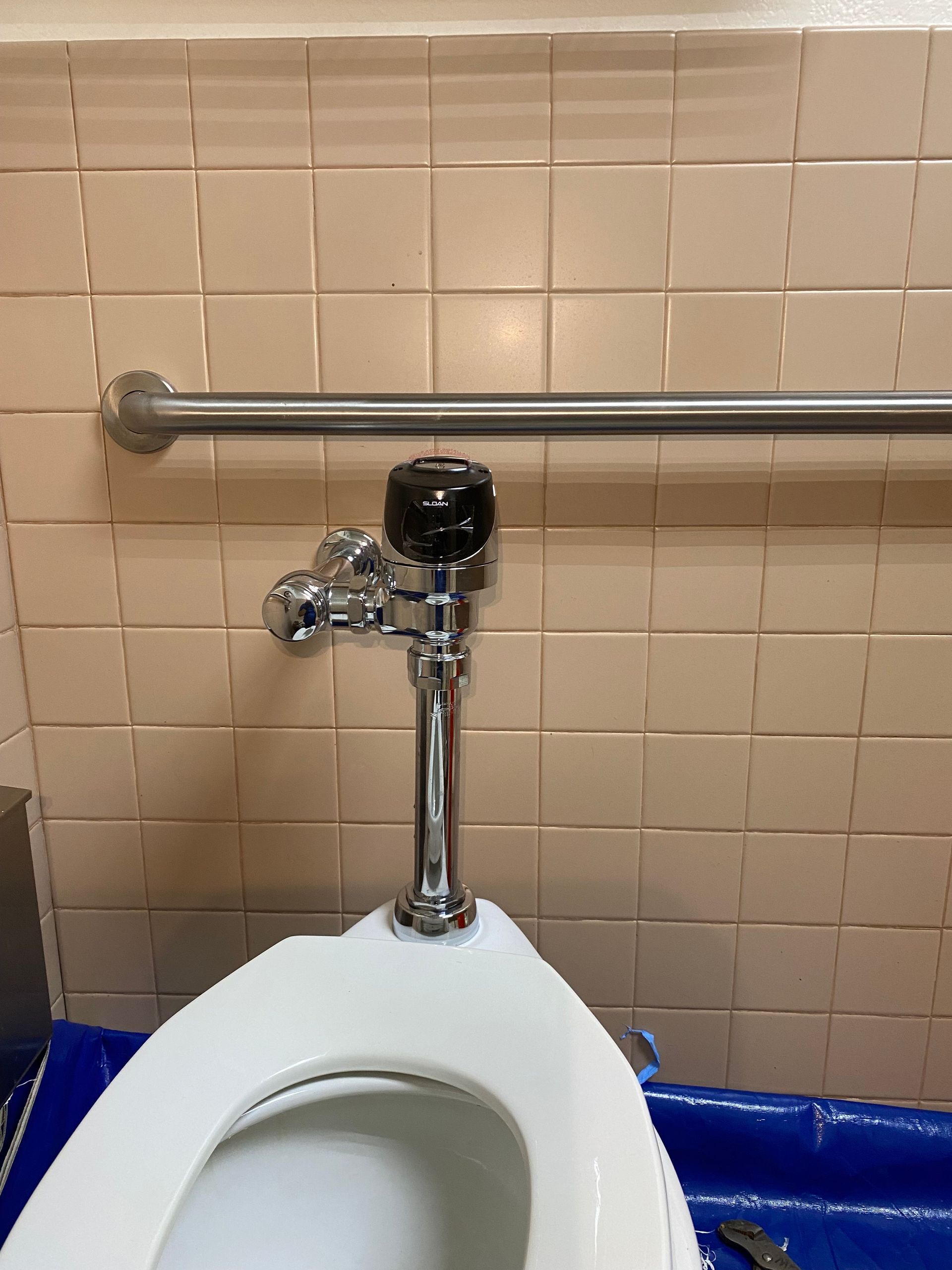 A toilet is sitting in a bathroom next to a hand rail.