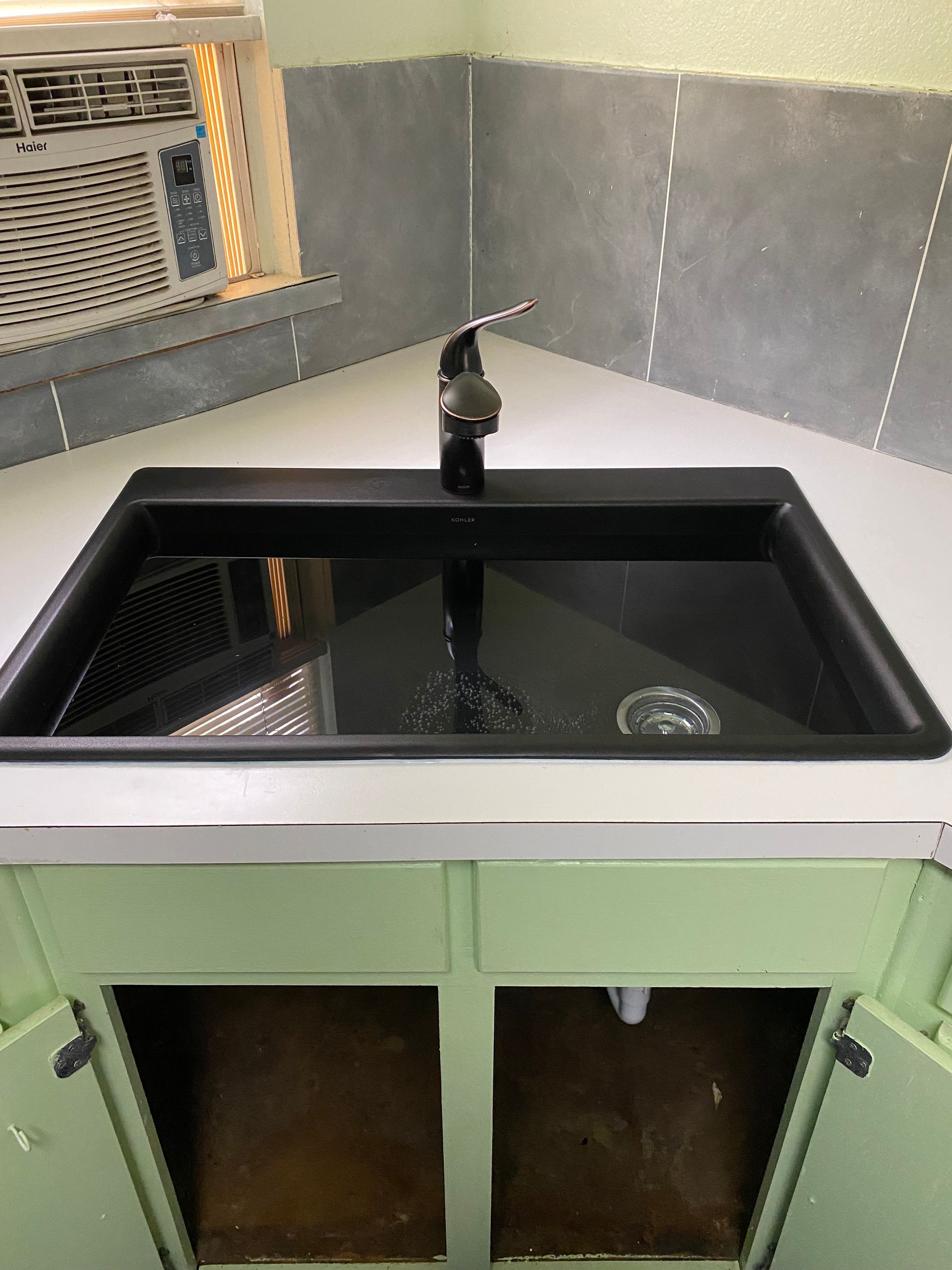 A black sink is sitting on a counter in a kitchen.