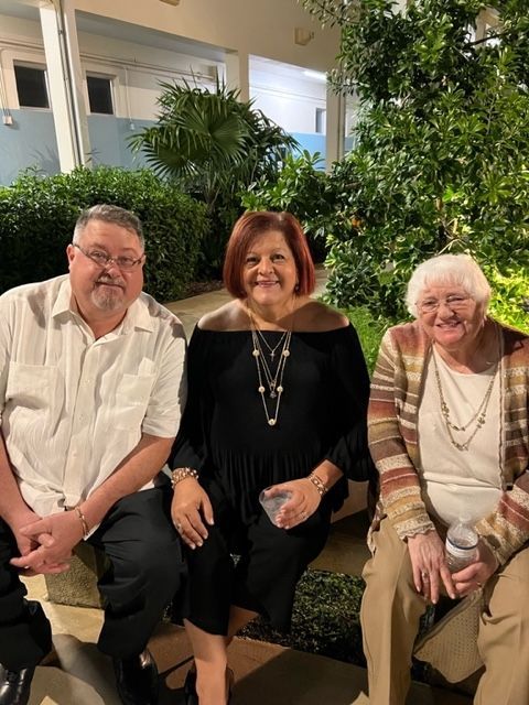 A man and two women are sitting next to each other on a bench.
