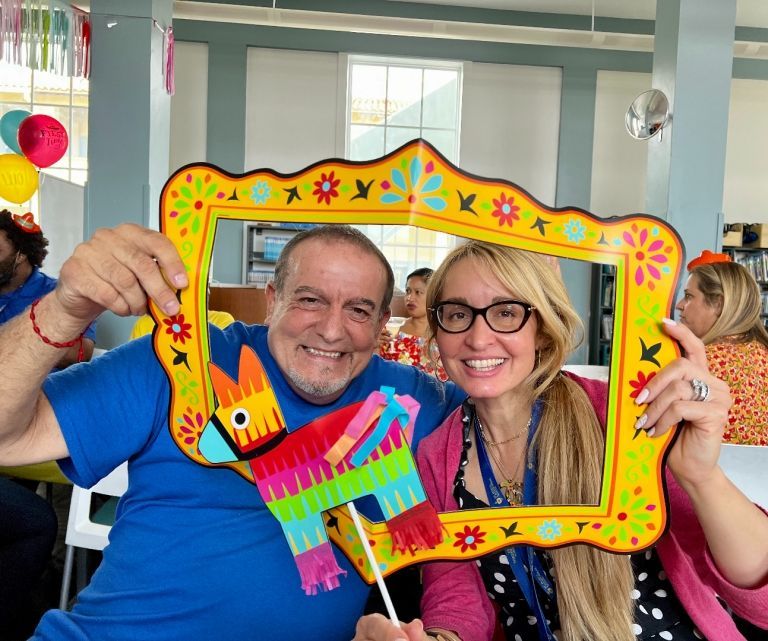 A man and woman holding a picture frame with a pinata in it