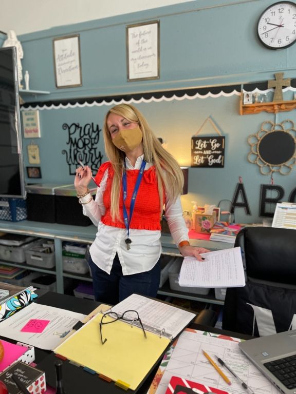 A woman wearing a mask is standing in a classroom