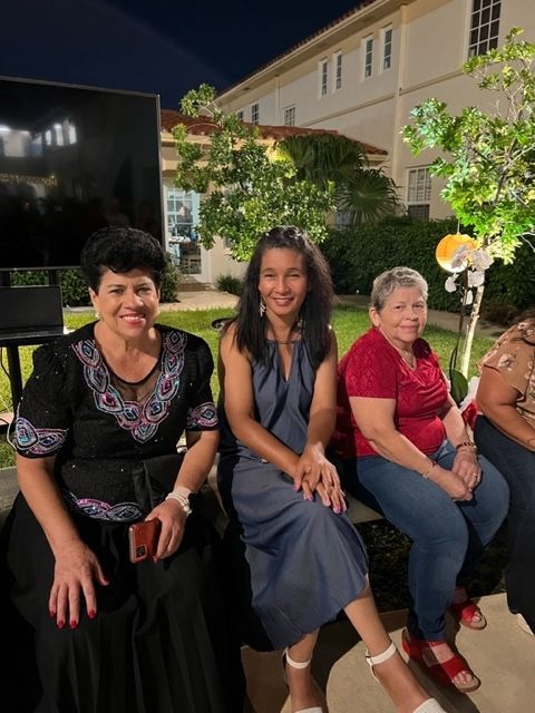 A group of women are sitting on a bench outside at night