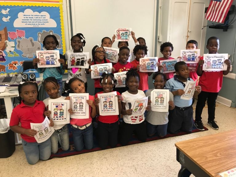A group of children are holding up pictures in a classroom