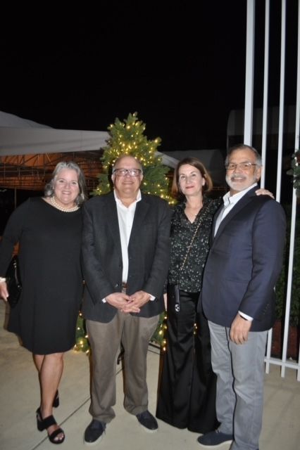 A group of people are posing for a picture in front of a christmas tree.