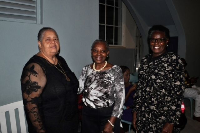 Three women standing next to each other in a dark room