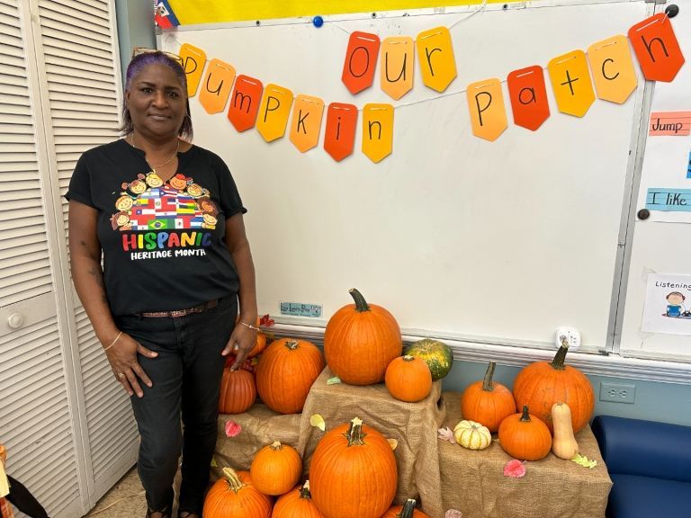 A woman stands in front of a white board that says pumpkin patch