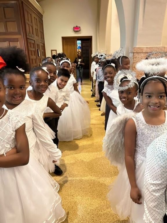 A group of young girls dressed as angels are standing in a church.