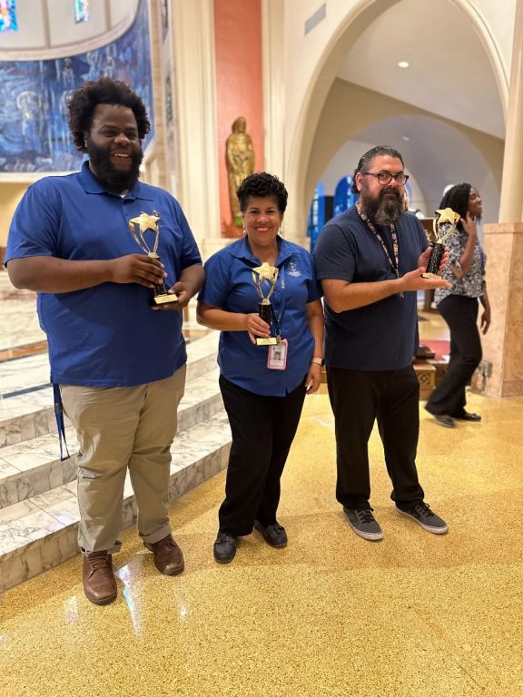 A group of people standing in a church holding trophies