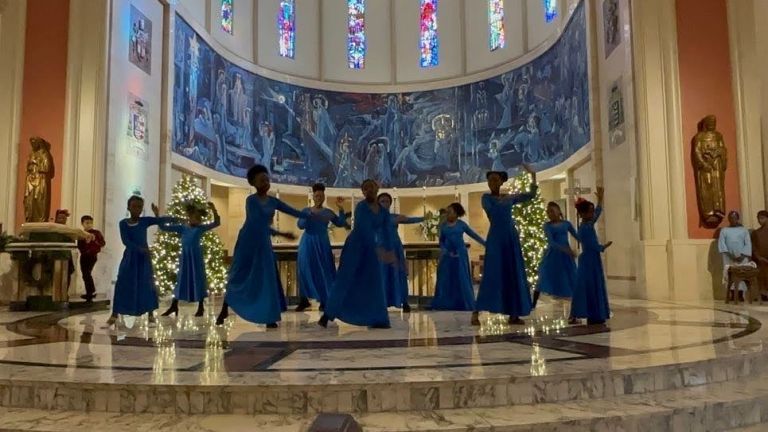 A group of women in blue dresses are dancing in a church.